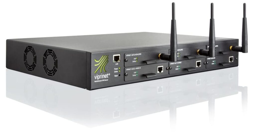 The picture shows the Ascend Viprinet Multichannel VPN Router 2610. The router is a technical device with many connections and antennas. It has a rectangular housing with rounded corners and is mostly transparent so that you can see the various components inside. The router stands on a white background and the cable connections are clearly visible. Compared to other Ascend Viprinet routers, the 2610 router is larger and more powerful