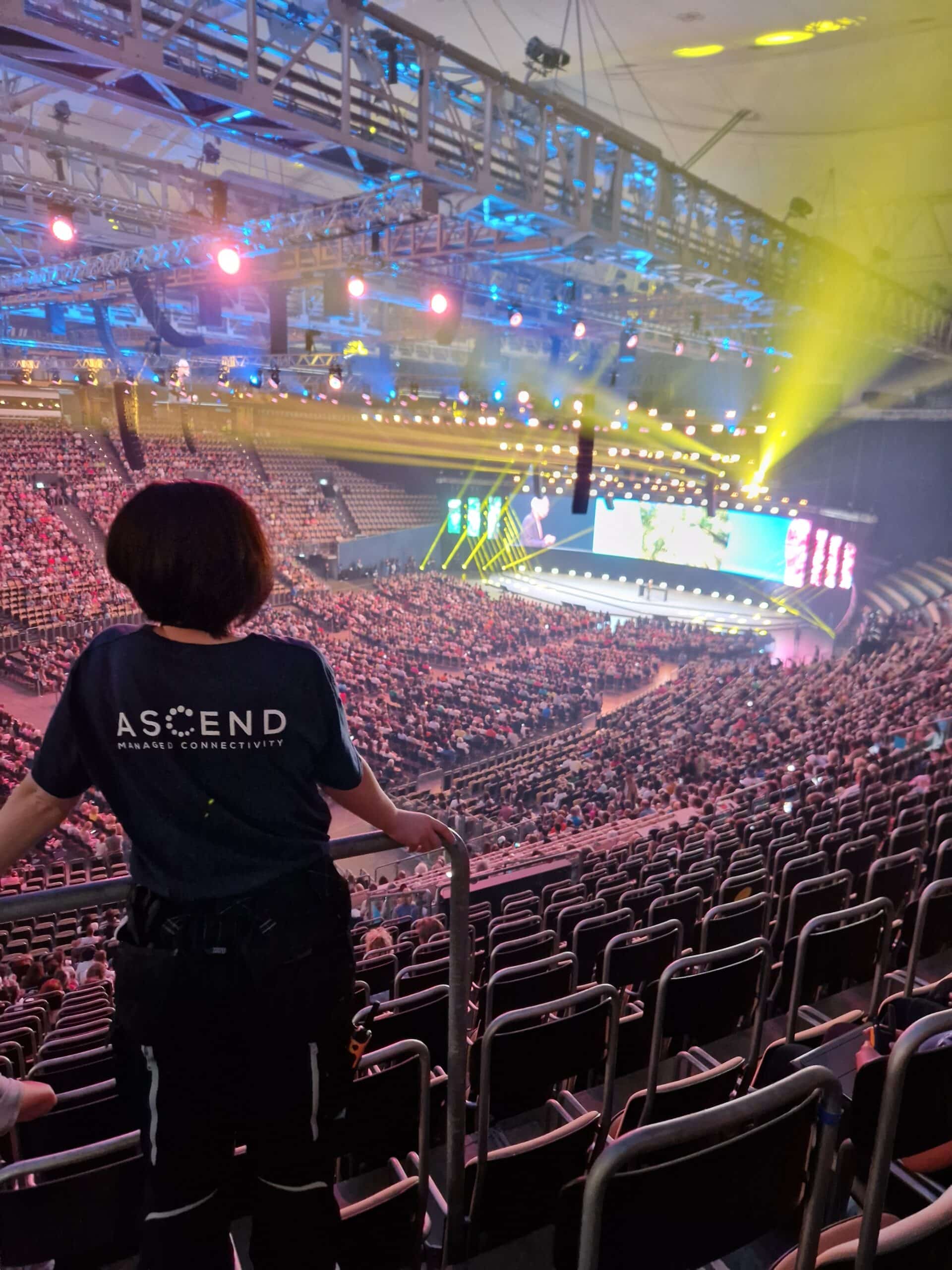 Colleague from the Ascend team stands in front of a crowd in the Olympic Hall at a major event