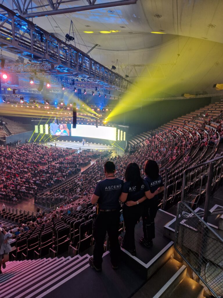 Audience at event in illuminated arena.