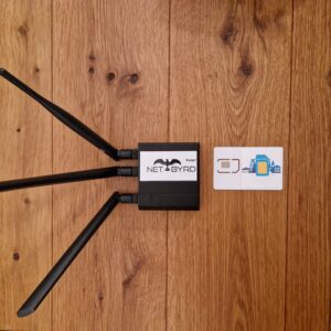 WLAN router with three antennas and network card on wooden table.